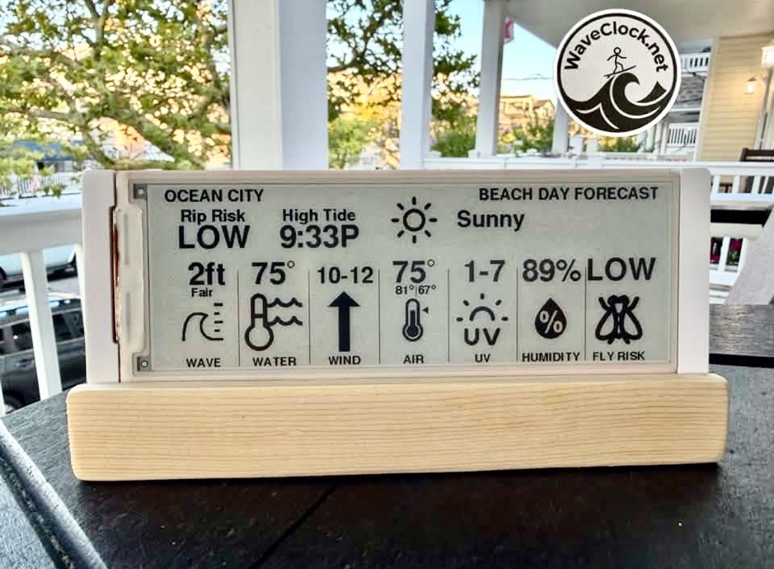 Wave Clock on a porch railing showing the Beach Day Forecast screen, with rip risk, high tide, wave and water conditions, wind, UV, humidity, and fly risk for Ocean City