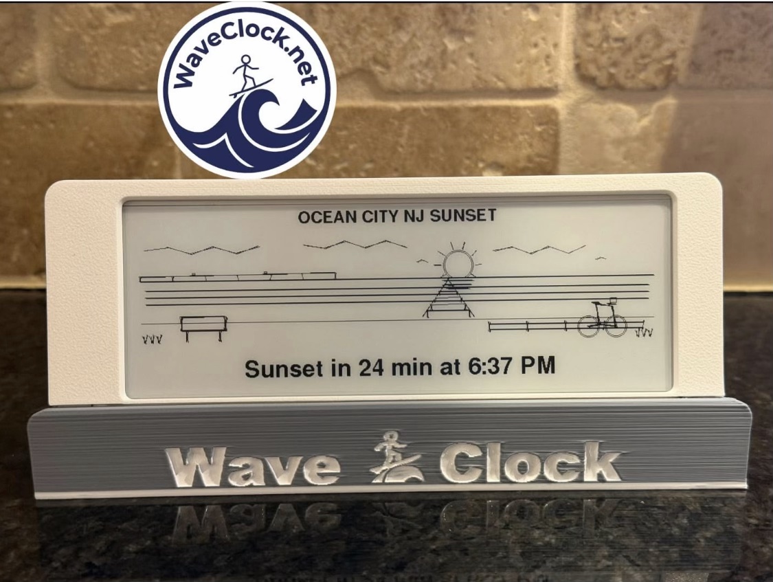 Wave Clock with its new white face plate and brushed stand, displaying the Sunset screen for Ocean City, NJ.